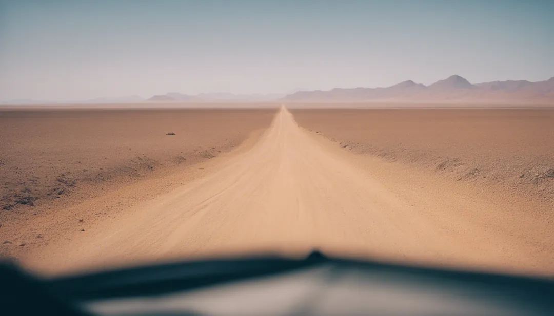 A long winding gravel road in the Namib desert as seen from the inside of a car